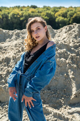 pretty lady in blue overalls walks in a sand quarry, active way