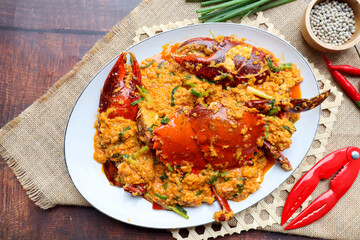 Thai curry crab - Famous stir fried crab with curry powder, vegetables and egg - Thai food called Poo Pad Pong Kari, Top view on wood background