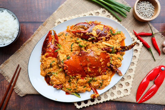 Thai curry crab - Famous stir fried crab with curry powder, vegetables and egg - Thai food called Poo Pad Pong Kari, flat lay on wood background
