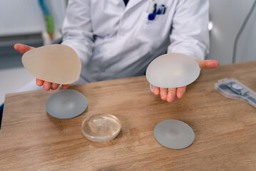 Doctor holding implants in his hands. Medical silicon implants in doctor hands. - obrazy, fototapety, plakaty