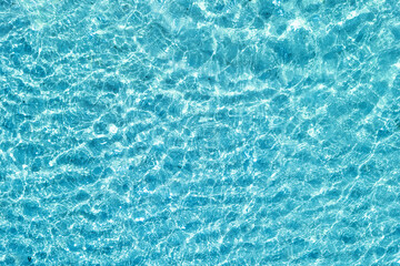Background shot of aqua water surface. Swimming pool with sunny reflections.