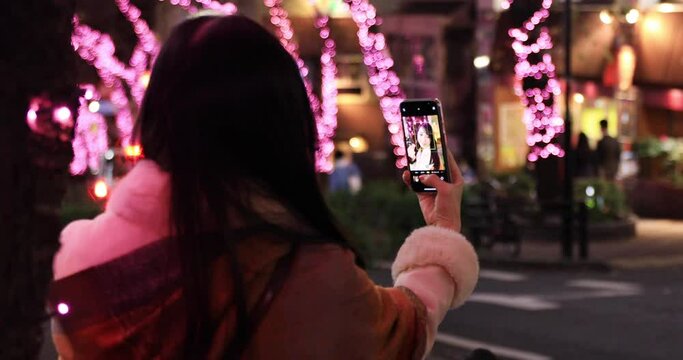 Selfie shot of Japanese woman with illumination on the downtown street closeup