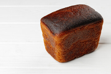 Loaf of rye bread on white wooden table