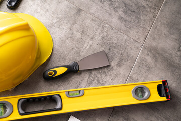 Contractor theme. Tool kit of the contractor: yellow hardhat, libella and tools on the gray tiles...