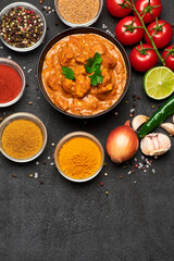 Plate of Traditional Chicken Curry and spices on dark concrete background