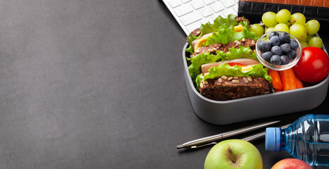 Healthy office lunch box with sandwich and fresh vegetables