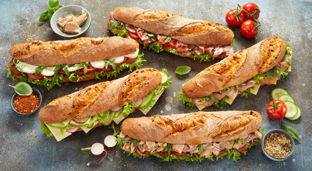 Various sub sandwiches and ingredients on table