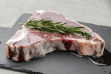 Raw t-bone steak marinated in oil on gray table
