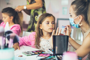 Two little girls in a make-up studio. Focus is on little girl.