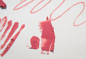 The red color of the lipstick is smeared with a zigzag stroke and lines on the white background