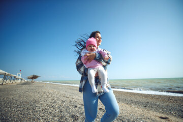 A woman with a child by the sea. Beautiful mother plays with her baby by the sea. High quality photo