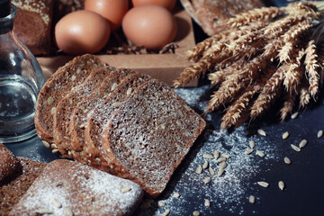 Fresh loaves of bread with wheat and gluten on a black table. Bakery and grocery concept. Fresh,...
