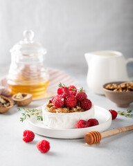 camembert cheese with raspberries, honey, walnuts and thyme . White background, selective focus, 