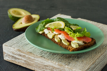 Sandwich with smoked salmon soft cheese, lattice and avocado. Concept for a tasty and healthy meal. Food on a plate.
