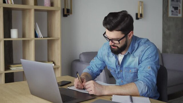 Focused young caucasian businessman in eyeglasses holding video conference call
