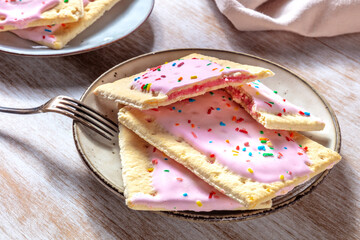 Strawberry pop tarts on a plate on a wooden table - obrazy, fototapety, plakaty