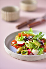 Fresh vegetable salad in a gray plate on a powdery background.