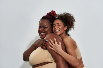 Two happy african american women in underwear with different body size having fun, posing together...