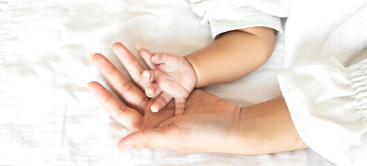 Portrait of enjoy happy love family asian mother playing with adorable little asian baby.Mom touching with cute son moments good time in a white bedroom.Love of family concept