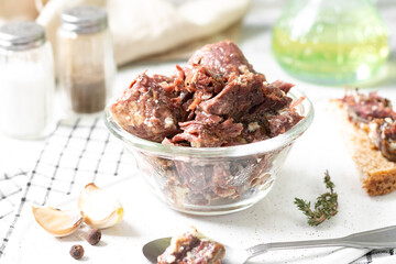 Beef stew in a glass bowl on a light gray table closeup