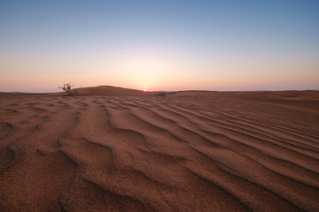 Sunset over the sand dunes in the desert.