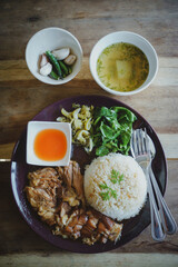 Stewed pork leg on rice with side bowl on wooden table.Thai food