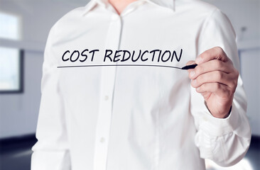 Businessman hand holds a pen and underlines the words cost reduction on virtual screen. Business finance concept.