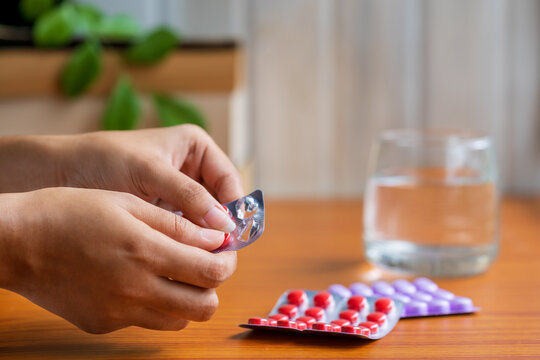Woman Taking Pills or Medicine. A female person taking medicines or antibiotic tablets with a glass of water. Concept for sick at home treatment and medication, covid-19 immunity booster, vitamins.