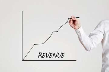 Businessman hand draws a rising line graph with the word revenue. Increase in business revenue