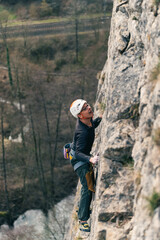 Male climber anticipates his next move while climbing vertical wall.