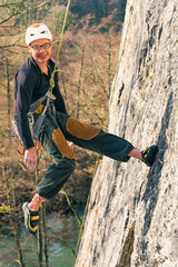 Smiling man safely tied to a climbing rope in a beautiful sunny day.