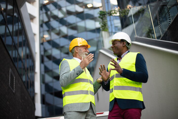 Engineer discussing the structure of the building with architects colleague at construction site.