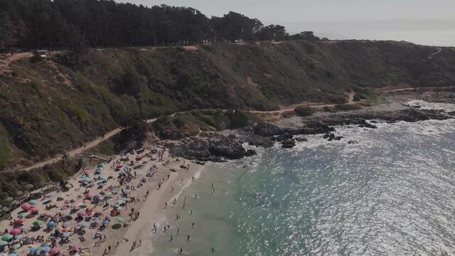 Aerial view over El Canelo beach at Chile on a sunny day with people in the beach's sand