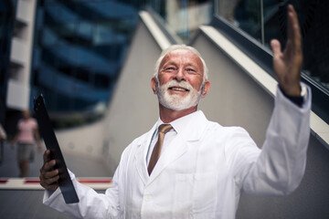 Senior doctor standing on street and writing on document.