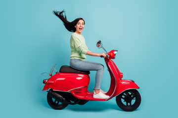 Fototapeta na wymiar Profile side view of lovely cheerful amazed girl riding moped having fun air blowing hair isolated over bright blue color background