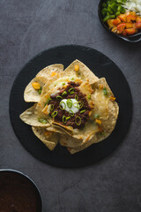 Overview of a plate of nachos with vegetables, cheese and beans