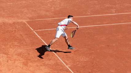 Tennis player athlete in action on clay tennis court during the game. Courage of professional athlete in competition. Individual sport