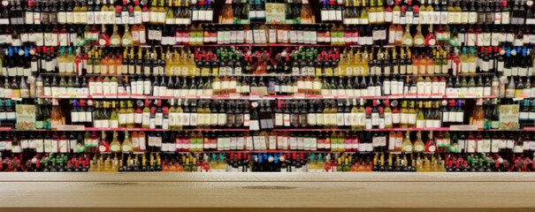 Blurred image of a liquor store with drinks. Wine bottles on the shelves. In the foreground is a table or counter. © serperm73