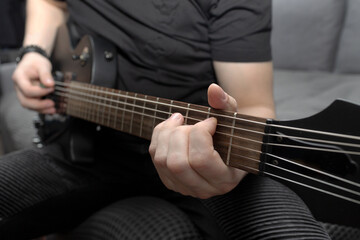 Fototapeta premium Musician playing black electric guitar. Guitar fretboard close-up. Learning to play the guitar. Self-development at home