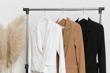 Corner in fashion atelier with fashionable tailored blazers hanging on a rack. Modern premium...
