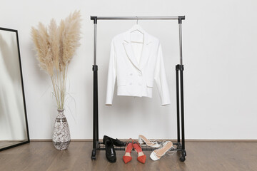 Women's Clothes. Clothes rack, white blazer and shoes in fashion atelier.