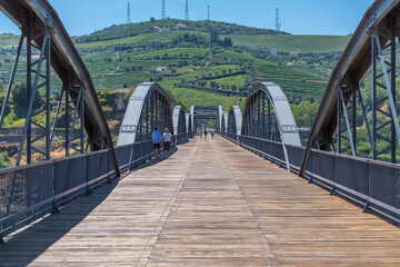 View at the metallic bridge over Douro river on the Peso da Regua downtown, with tourist people strolling