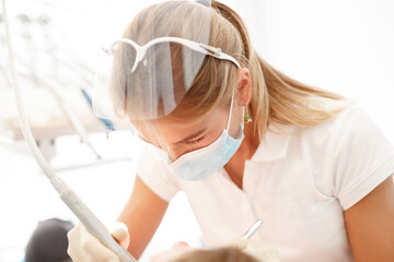 Naklejka premium Woman dentist working at her patients teeth. At the dentist office, examination.Dentist working in dental clinic with patient in the chair....