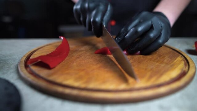 Close up shot of culinary master is cutting Red bell pepper to be prepared as a cooking ingredient in the restaurant's kitchen, Cut Red bell pepper on a white chopping board, 4K Footage.