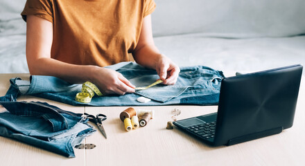 A woman is engaged in online training and looks at sewing lessons on a laptop. DIY Hobby Reuse Recycling Zero Waste