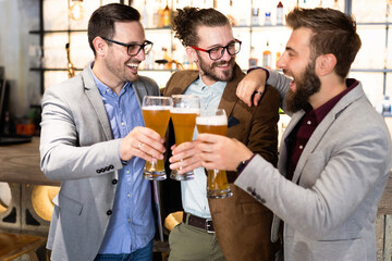 Leisure, friendship pub concept. Happy male friends drinking beer and clinking glasses at bar or pub
