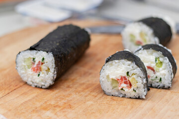 Cook's hands close-up. A chef makes sushi and rolls from rice, red fish, avocado and philadelphia cheese. step by step.