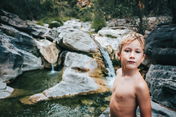 Shirtless boy alone in a wild forest proud showing strength