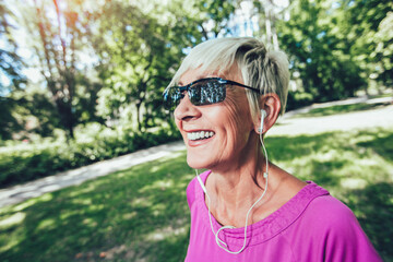 Elderly woman running with headphones in the park