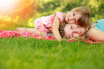 happy mother with baby in nature lying on the grass in the park